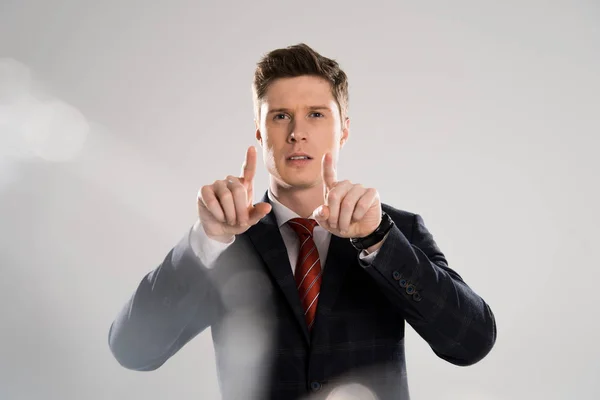 Selective focus of young businessman touching something on grey — Stock Photo