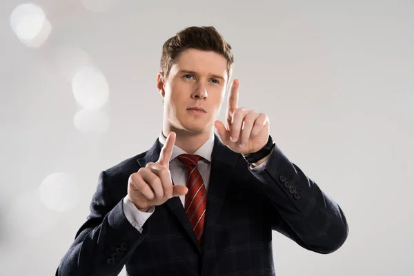 Selective focus of handsome businessman touching something on grey — Stock Photo