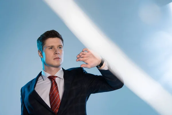 Selective focus of young handsome businessman gesturing on blue — Stock Photo