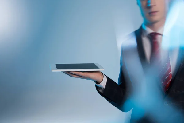 Selective focus of young business man holding digital device on blue — Stock Photo
