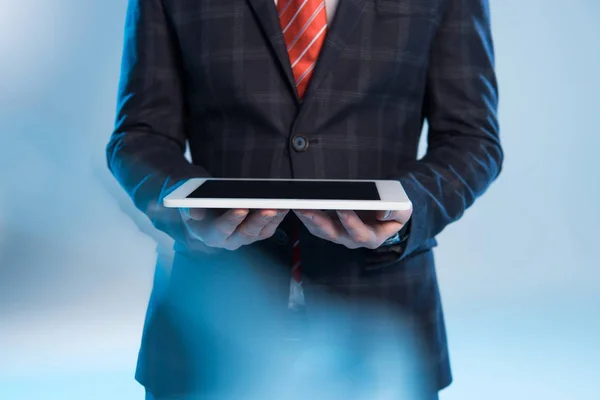 Enfoque selectivo de hombre de negocios celebración de tableta digital en azul - foto de stock