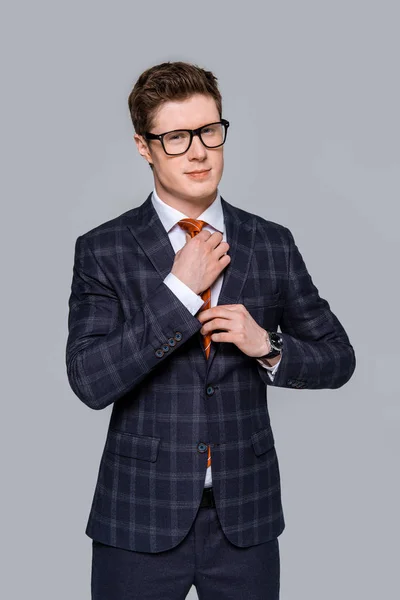 Handsome stylish businessman adjusting tie isolated on grey — Stock Photo