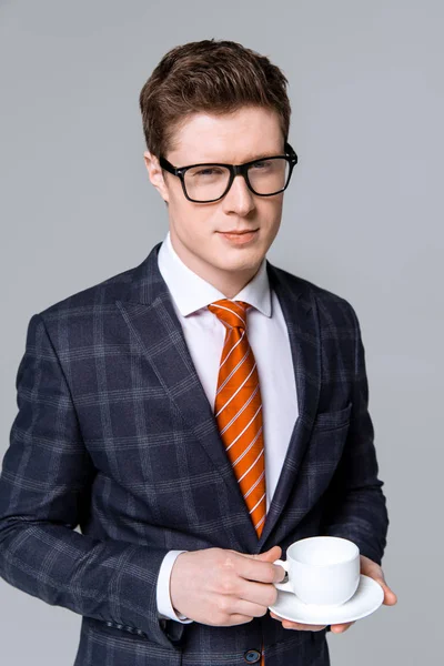 Handsome stylish businessman holding cup of coffee isolated on grey — Stock Photo