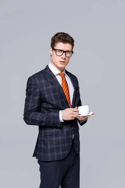 Elegante uomo d'affari in possesso di tazza di caffè isolato su grigio — Foto stock