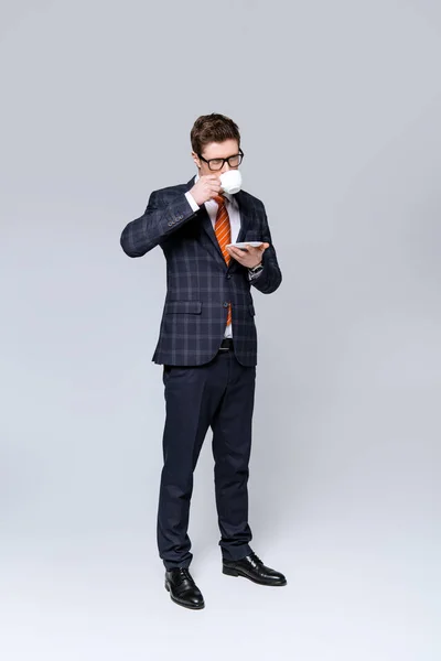 Stylish businessman in formal wear drinking coffee isolated on grey — Stock Photo