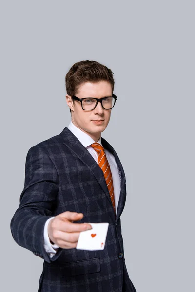 Elegante hombre de negocios sosteniendo naipe aislado en gris — Stock Photo