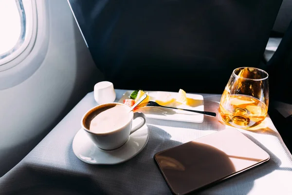 Passenger table in airplane with drinks, snacks and digital tablet with blank screen — Stock Photo