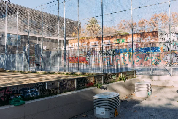 BARCELONA, SPAGNA - 28 DICEMBRE 2018: parco giochi con recinzione ad alta rete metallica e graffiti a parete — Foto stock