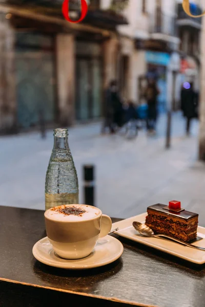 Kaffeetasse, Flasche Mineralwasser und Untertasse mit Kuchen auf der Theke, Barcelona, Spanien — Stockfoto