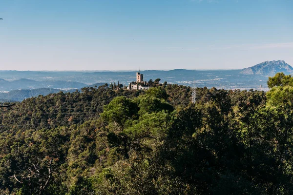 Vista panorámica del castillo y las colinas cubiertas de árboles verdes, barcelona, España - foto de stock