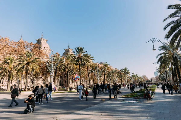 Barcelona, Spanien - 28. Dezember 2018: Menschen gehen entlang einer breiten Gasse mit hohen grünen Palmen — Stockfoto