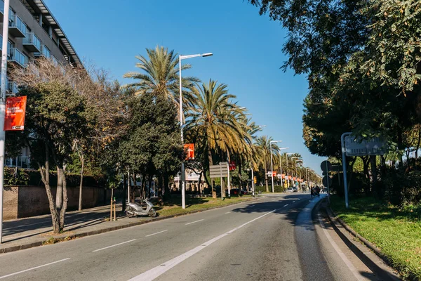 БАРСЕЛОНА, Испания - 28 ДЕКАБРЯ 2018 года: уютная улица с зелеными деревьями, растущими вдоль дороги — стоковое фото
