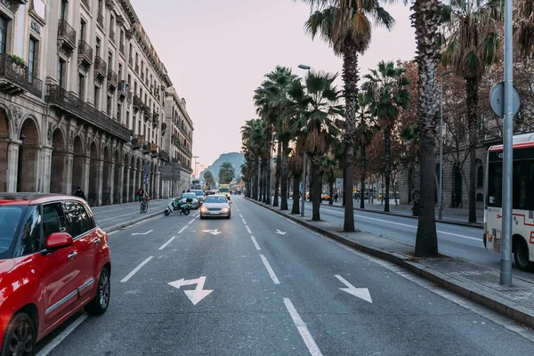 BARCELONE, ESPAGNE - 28 DÉCEMBRE 2018 : rue animée avec des bâtiments, des palmiers et des voitures circulant sur la chaussée — Photo de stock