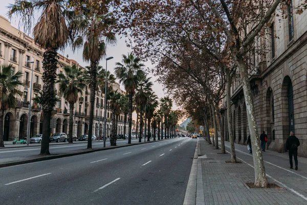 БАРСЕЛОНА, ИСПАНИЯ - 28 ДЕКАБРЯ 2018 года: улица города с проезжей частью со зданиями и пальмами — стоковое фото