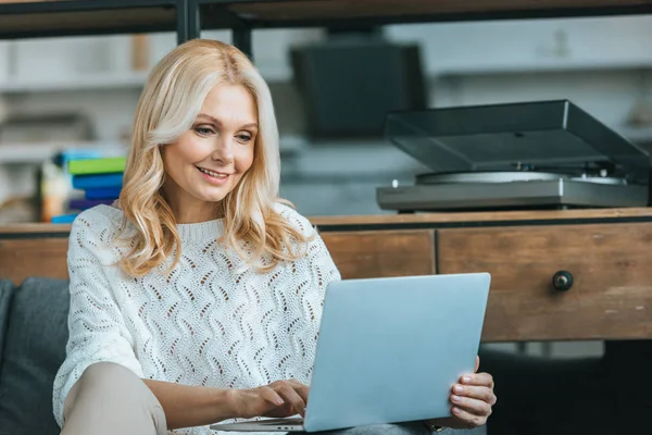 Fröhliche Frau mit blonden Haaren mit Laptop zu Hause — Stockfoto