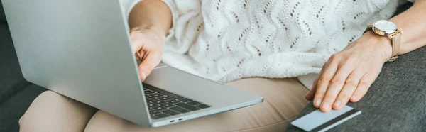 Vista ritagliata della donna che utilizza il computer portatile vicino alla carta di credito a casa — Foto stock