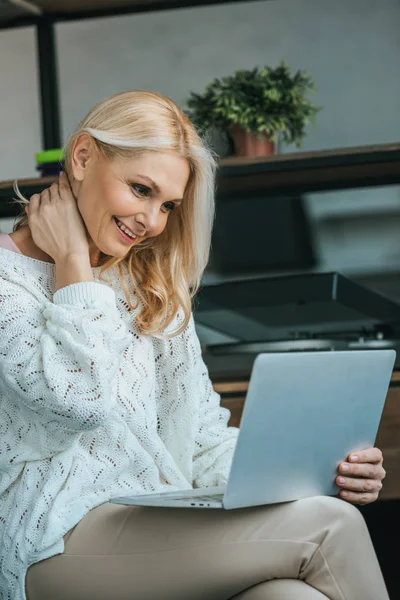 Happy woman smiling while looking at laptop — Stock Photo