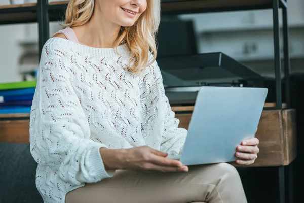 Corte vista feliz mulher sorrindo enquanto olha para laptop em casa — Fotografia de Stock