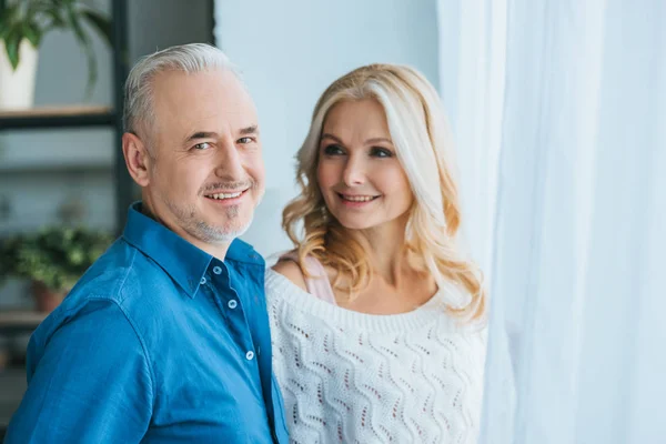 Feliz pareja sonriendo mientras está de pie en casa - foto de stock