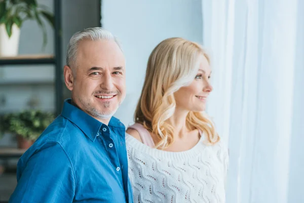 Couple joyeux souriant tout en se tenant à la maison — Photo de stock