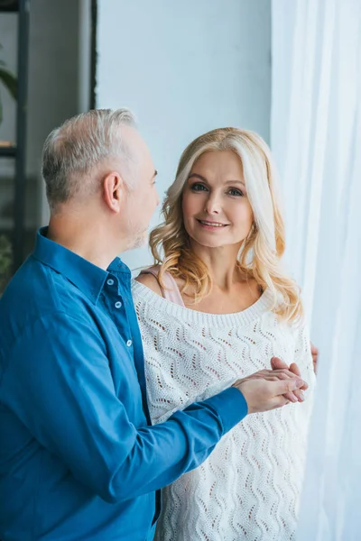 Uomo guardando sorridente moglie mentre si tiene per mano a casa — Foto stock
