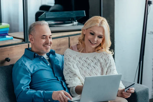 Couple heureux en utilisant un ordinateur portable tout en magasinant en ligne à la maison — Photo de stock