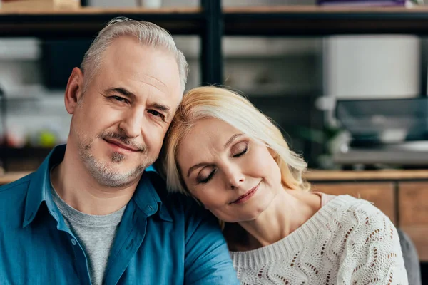 Feliz marido sonriendo cerca de esposa durmiendo en casa - foto de stock