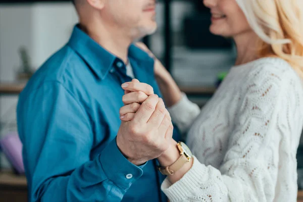 Vista recortada de marido y mujer felices tomados de la mano mientras bailan - foto de stock