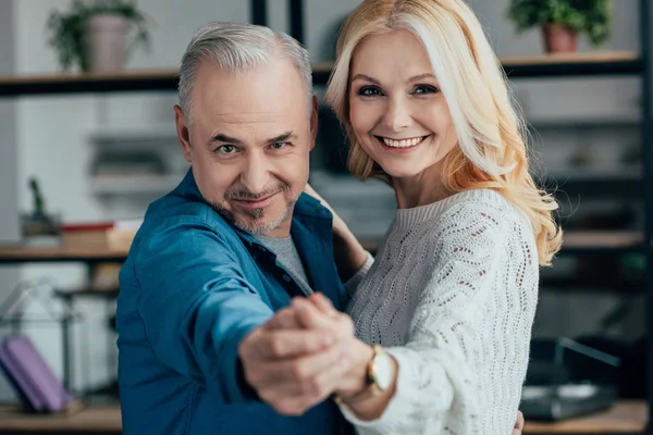 Selective focus of happy husband and wife holding hands while dancing — Stock Photo