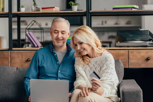 Couple souriant regardant ordinateur portable et achats en ligne à la maison — Photo de stock