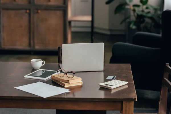 Gadgets in der Nähe von Tasse, Büchern und Taschenrechner auf dem Schreibtisch — Stockfoto