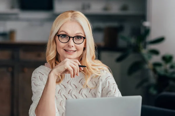 Attractive woman in glasses sitting near laptop at home — Stock Photo