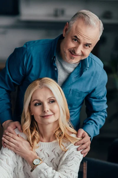 Handsome man embracing cheerful wife at home — Stock Photo