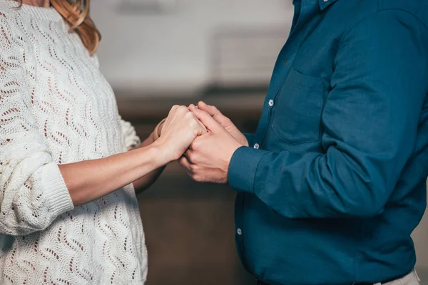 Vista recortada de la esposa y el marido tomados de la mano en casa - foto de stock