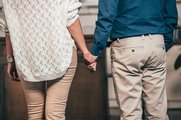 Vista recortada de la pareja de pie y cogidas de la mano - foto de stock