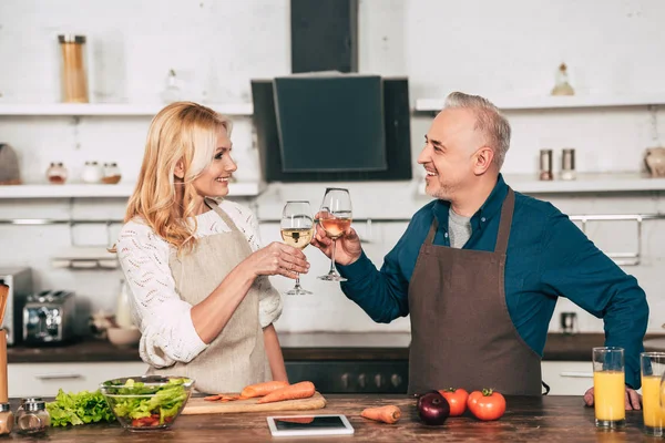 Schöner Ehemann klimpert mit lächelnder Frau in Küche mit Weingläsern — Stockfoto