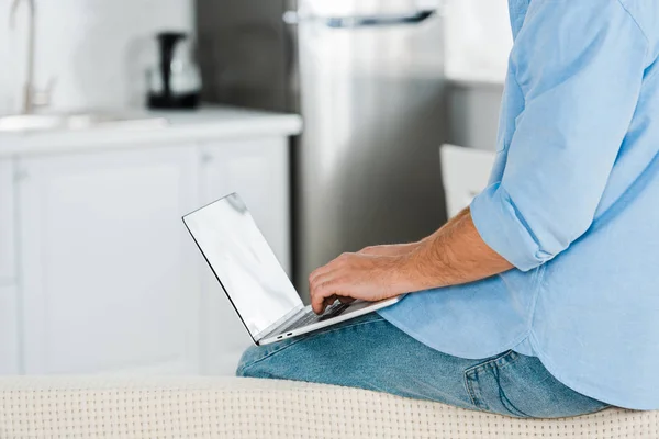 Vista cortada do homem sentado e usando laptop em casa com espaço de cópia — Fotografia de Stock