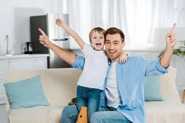 Aufgeregter Vater und Vorschulsohn umarmen sich, jubeln und schauen zu Hause in die Kamera — Stockfoto