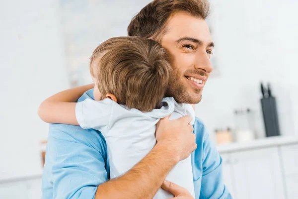 Souriant beau père câlin enfant d'âge préscolaire à la maison — Photo de stock