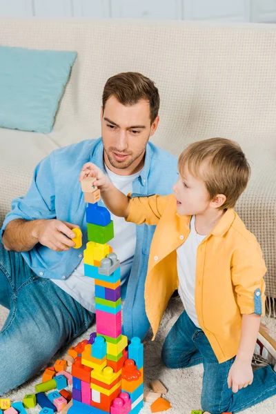 Vater und Vorschulsohn spielen zu Hause mit bunten Bausteinen — Stock Photo