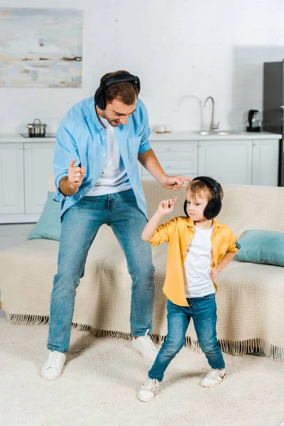 Père avec enfant d'âge préscolaire fils dans écouteurs écouter de la musique et danser à la maison — Photo de stock