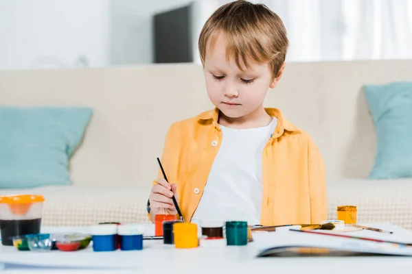 Foco seletivo de desenho bonito menino pré-escolar com pincel em casa — Fotografia de Stock