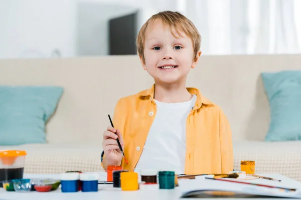 Adorable smiling preschooler boy looking at camera while drawing at home — Stock Photo