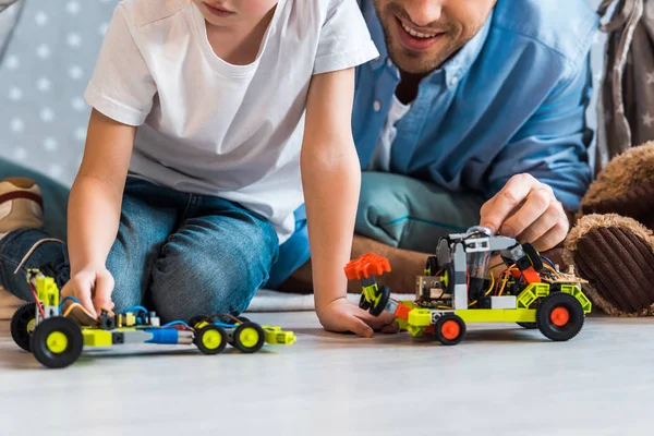 Vista recortada de padre e hijo preescolar jugando con coches de juguete en casa - foto de stock