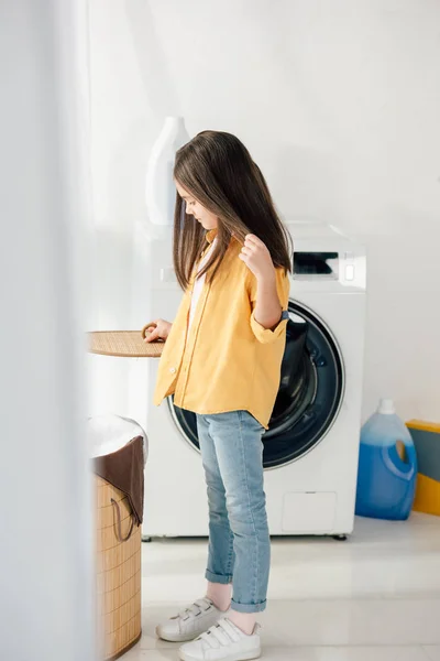 Enfant debout et tenant panier couverture dans la buanderie — Photo de stock