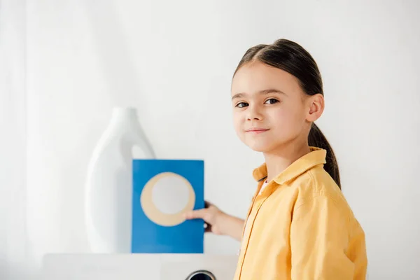 Selective focus of child with washing powder in laundry room — Stock Photo