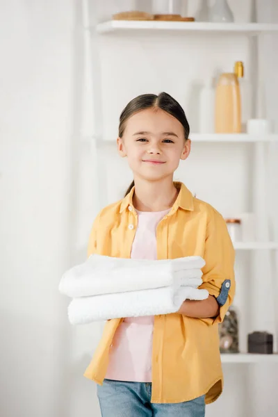 Selective focus of child in yellow shirt holding towels at home — Stock Photo