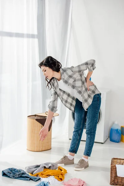 Woman standing near baskets and holding backache in laundry room — Stock Photo