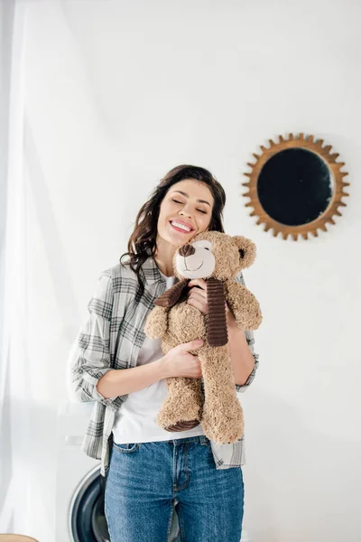 Femme tenant ours jouet et souriant à la maison — Photo de stock