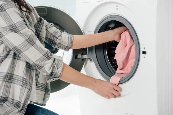 Vista cortada da mulher colocando roupas na máquina de lavar roupa na lavanderia — Fotografia de Stock